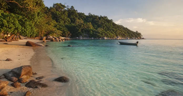 Clear water and pale sand on a Malaysian island beach at golden hour