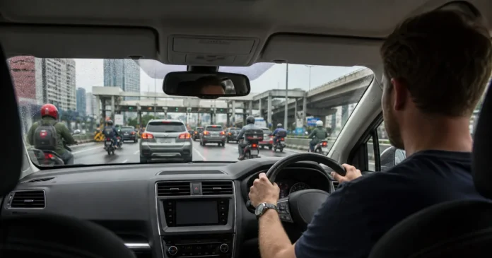 Expat driver navigating wet Kuala Lumpur traffic with motorcycles filtering between lanes